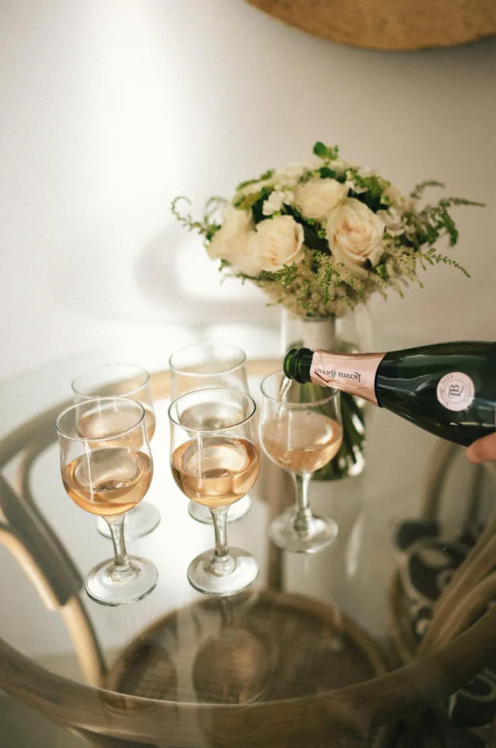 Sekt wird in Gläser vor einem Brautstrauß eingeschenkt